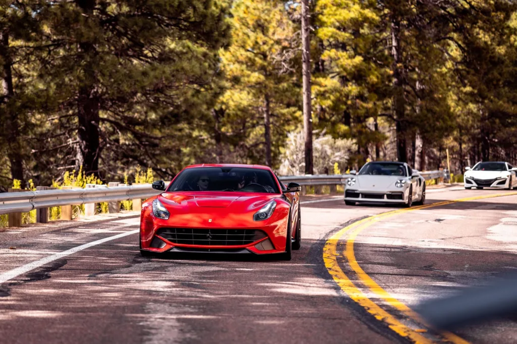 Red Ferrari F12 and Porsche 911 Turbo S on a pine forest road with PHXDriven